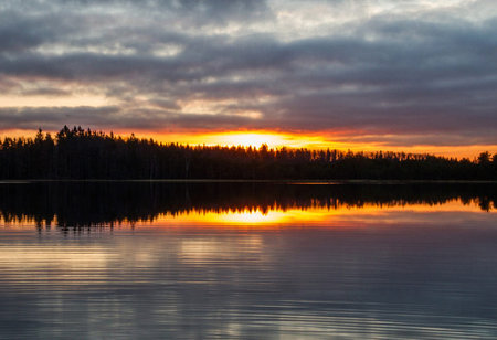 beautiful sunset over the lake in the forest with clouds and reflectionsの写真素材