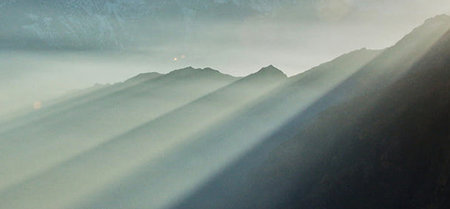 Sun rays shining through the clouds in the mountains. Panoramic view.の写真素材