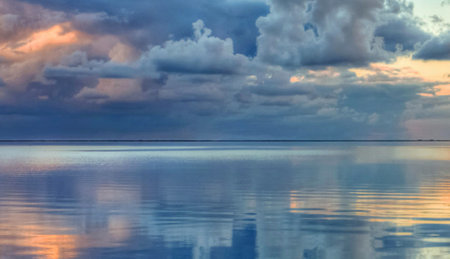 Clouds reflected in the water of a lagoon at sunset.の写真素材