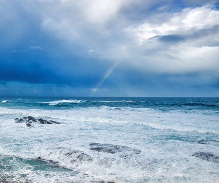 Rainbow over the ocean in stormy weather. Nature composition.の写真素材