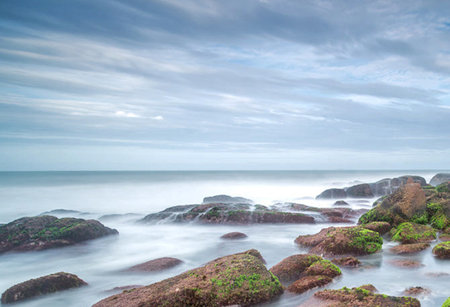 Long exposure of a seascape with rocks covered with green moss