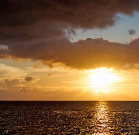 sunset on the sea with clouds and sun rays on the waterの写真素材