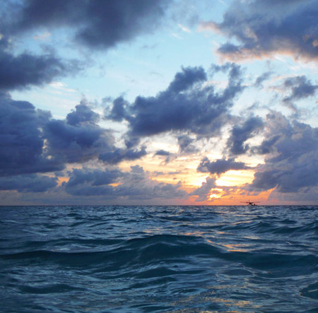 Beautiful sunset in the sea. Blue sky with clouds and sun.の写真素材