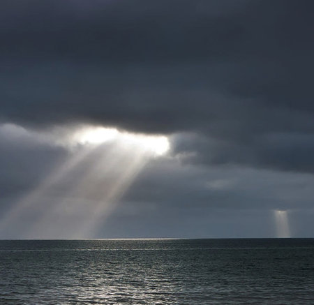 Seascape with sunbeams passing through the clouds over the sea