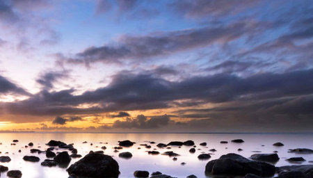 Sunset over the sea with rocks and reflections in the water.の写真素材