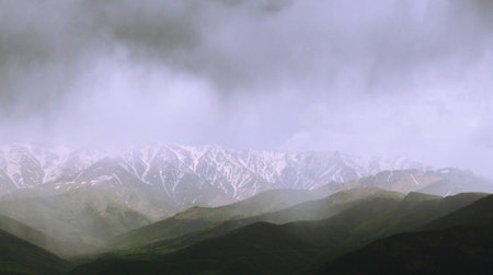 Mountain landscape with snow-capped peaks in the clouds.