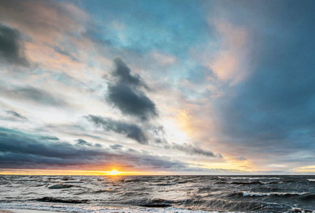 Baltic sea at sunset. Dramatic sky, glowing clouds, waves and water splashes. Epic seascape.の写真素材