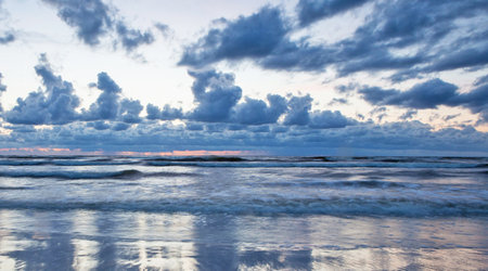 Beautiful seascape at sunset with clouds reflected in water.の写真素材