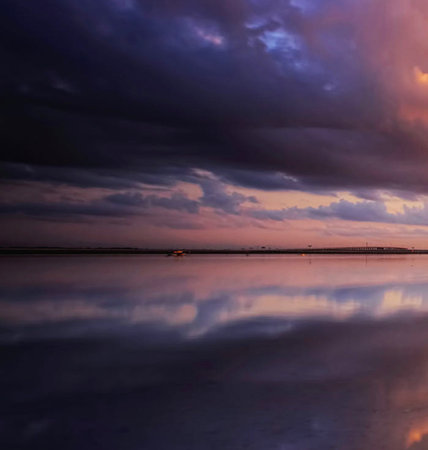 Beautiful sunset over the sea with dark clouds reflected in the waterの写真素材