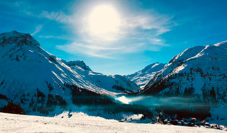Beautiful winter landscape with snow-capped mountains, lake and blue sky