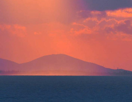 Sunset over the sea and mountains in the background. Beautiful landscape.