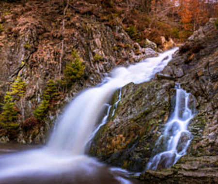 Long exposure of a waterfall flowing through a rocky gorge in the forest