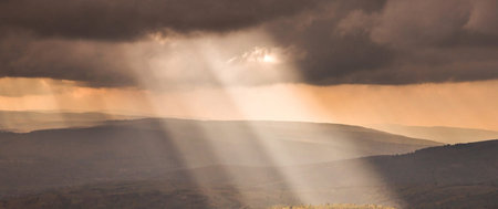 Sunset in the mountains. The sun rays through the clouds.の写真素材