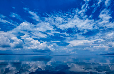Blue sky with white clouds reflected in water surface. Natural background.の写真素材