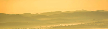 Panoramic landscape of foggy hills at sunrise in the mountainsの写真素材
