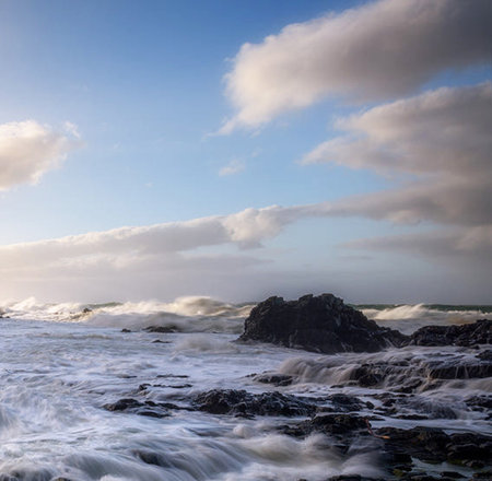 beautiful seascape with stormy ocean waves and rocks at sunset