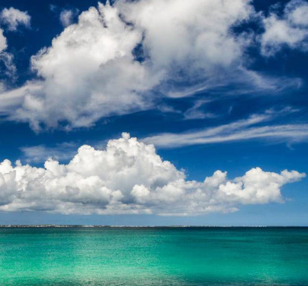 tropical beach under the blue sky with white clouds and sun rays