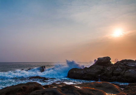 Beautiful sunset on the sea with waves crashing on the rocks.