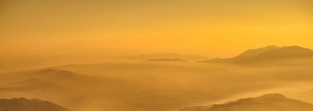 Panoramic view of the mountain range in the clouds at sunset
