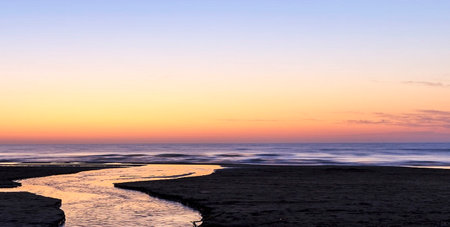 Sunset on the beach at low tide with reflection in the waterの写真素材