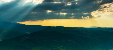Beautiful sunset in the mountains. The sun's rays make their way through the clouds.