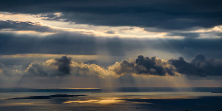Sunset over the sea with sunbeams passing through the clouds