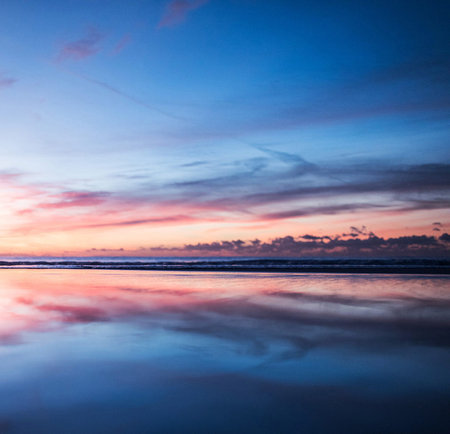 Beautiful sunset on the beach with reflection of clouds in water.
