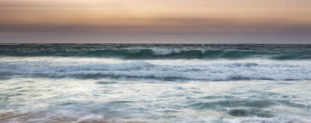 Panoramic view of a stormy sea at sunset, waves on the beach