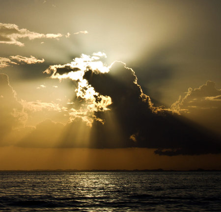 Sunset over the sea with rays of sunbeams and cloudsの写真素材