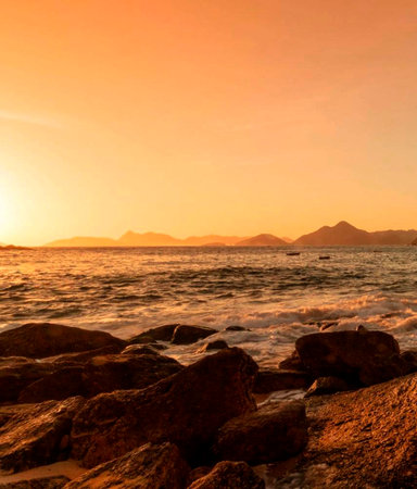 beautiful sunset over the sea with rocks and mountains in the background