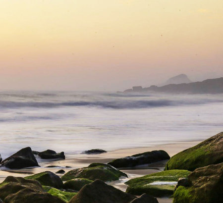 Sunset at the beach with rocks in the foreground and sea in the backgroundの写真素材