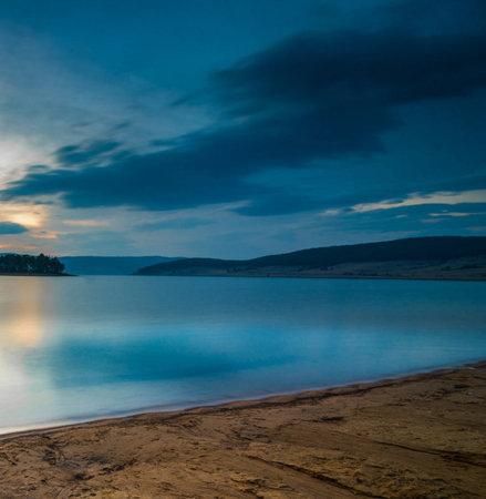 Dramatic sky over a lake at sunset with reflection in waterの写真素材