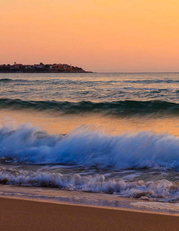 Beautiful sunset over the sea with waves crashing on the shore.