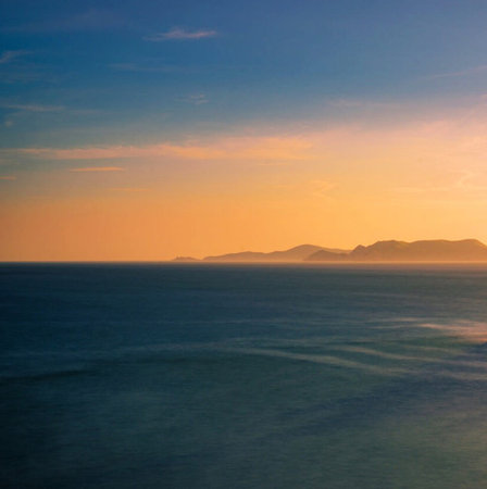 Sunset over the sea with mountains in the background, long exposureの写真素材
