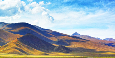 Beautiful grassland with mountains under blue sky in Tibet, Chinaの写真素材