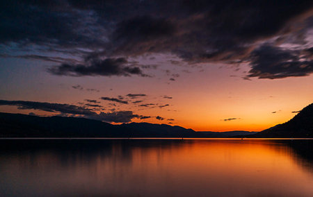 Sunset on the lake with mountains and clouds in the background.の写真素材