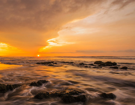 Beautiful sunrise on the beach with sea wave and rock at sunset timeの写真素材