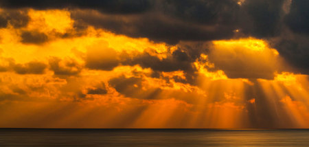 Beautiful sunset over the sea. Dramatic sky with glowing clouds and sunbeams.の写真素材