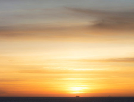 Sunset over the sea with a boat on the horizon in the foreground