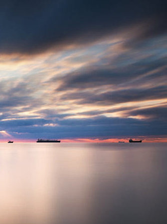 Beautiful sunset over the sea with ships in the foreground and dramatic sky