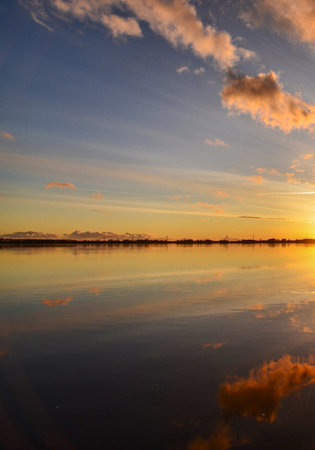 Beautiful sunset on the lake with reflection of clouds in the waterの写真素材