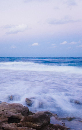 Sea waves crashing against the rocks on the beach in the evening.の写真素材