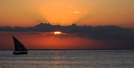 Sunset on the Caribbean Sea with a sailboat in the foreground