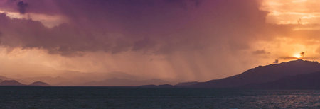 Panorama of a beautiful sunset over the sea with mountains in the backgroundの写真素材