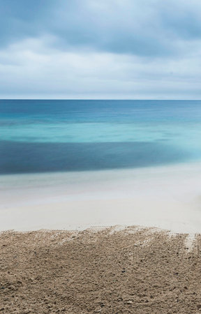 Tropical beach with turquoise water in cloudy day.
