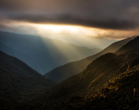Sunset in the mountains with sunbeams shining through the cloudsの写真素材