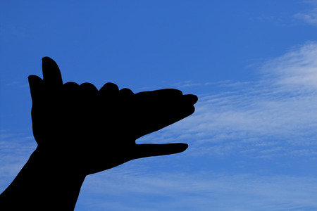Silhouette of hands like dog under blue sky.の写真素材