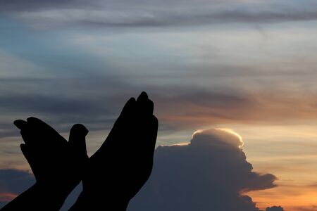 Silhouette of hands like bird under the sky at sunsetの写真素材