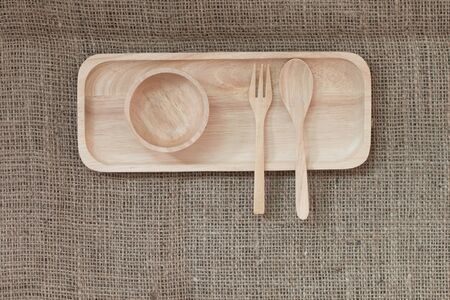 Top view : wooden spoon and wooden bowl in wooden tray on canvas texture background.の写真素材