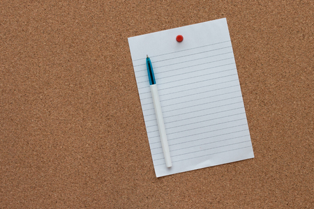 Paper pad with pen on cork board background.の写真素材